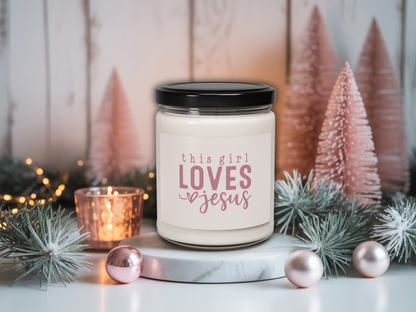 Candle jar with 'this girl LOVES Jesus' text in a decorative setting with Christmas trees and lights.