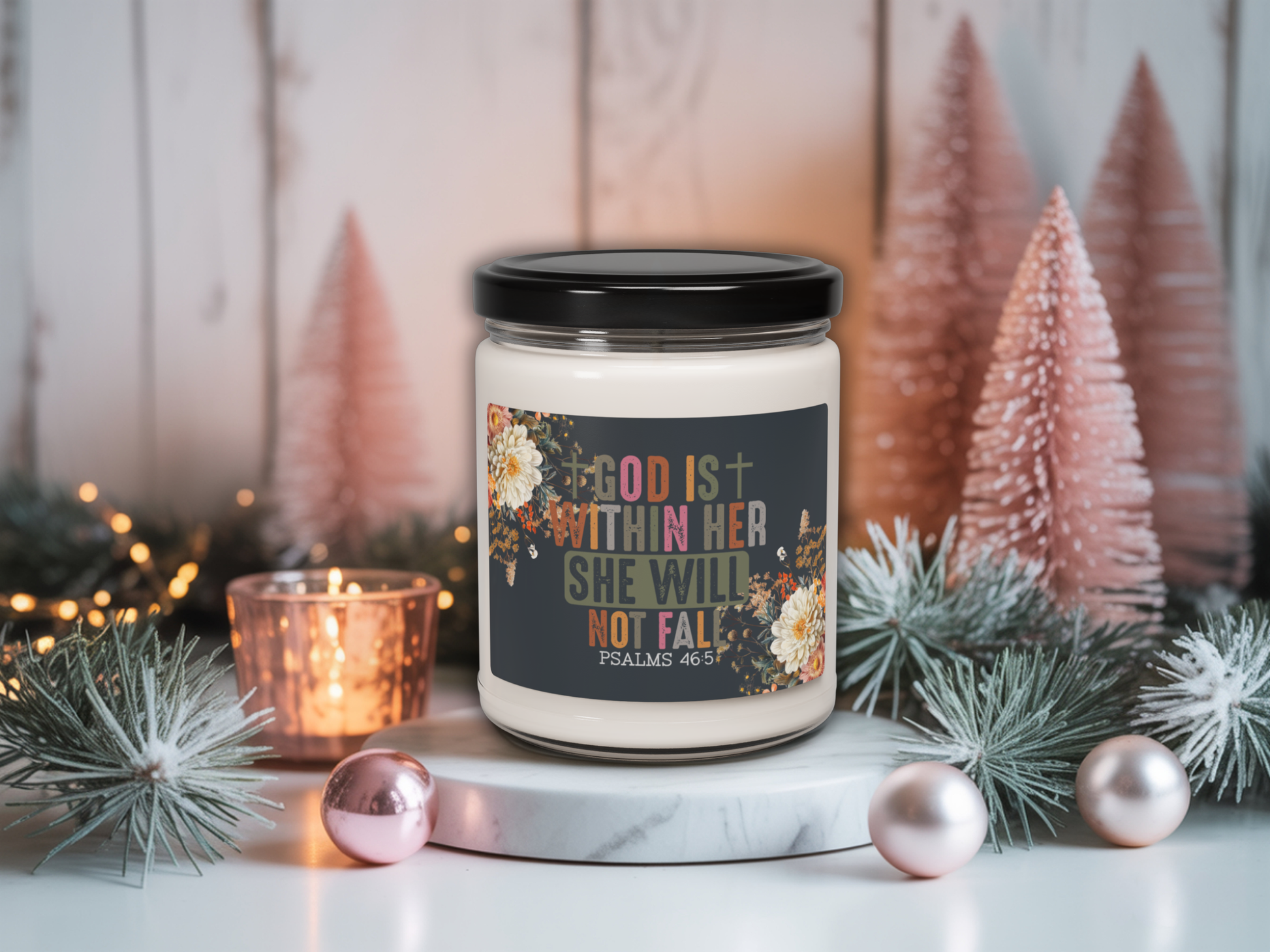 Candle with motivational quote in a decorative setting with Christmas trees and lights.