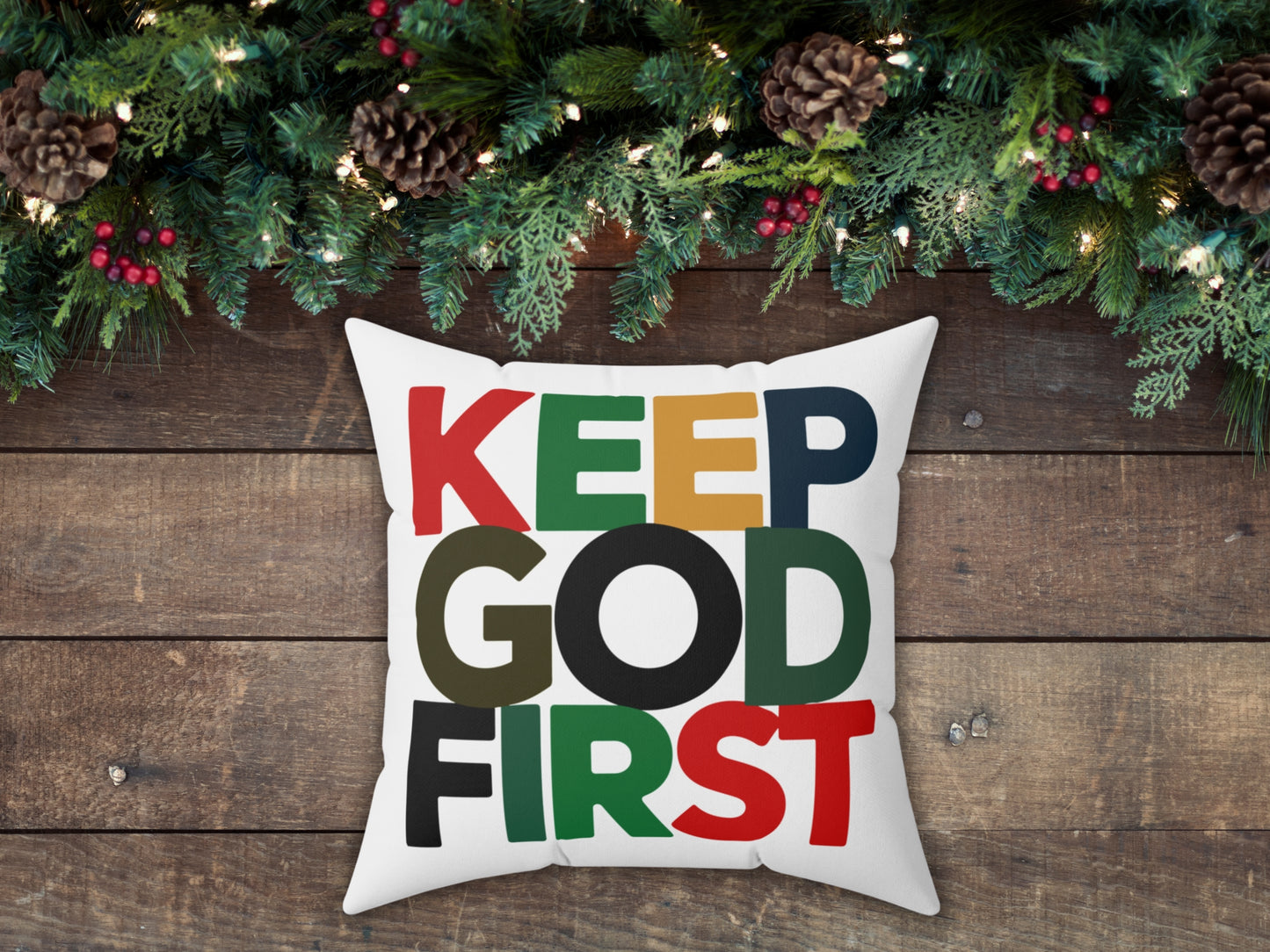 Decorative pillow with 'KEEP GOD FIRST' text on a wooden background with Christmas decorations.