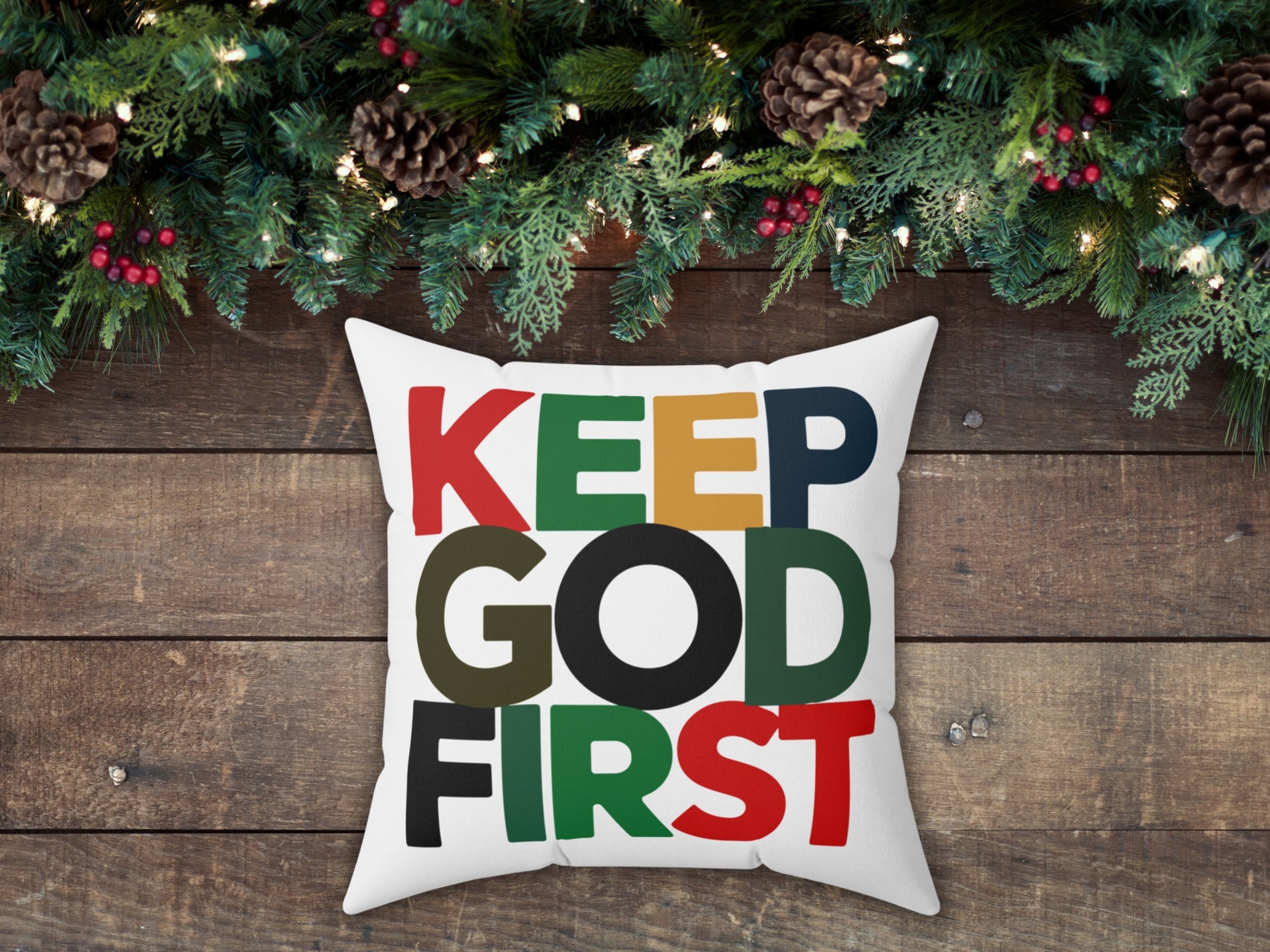 Decorative pillow with 'KEEP GOD FIRST' text on a wooden background with Christmas decorations.