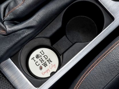 Car cup holder with a round coaster featuring 'Touchdown' text and graphics.
