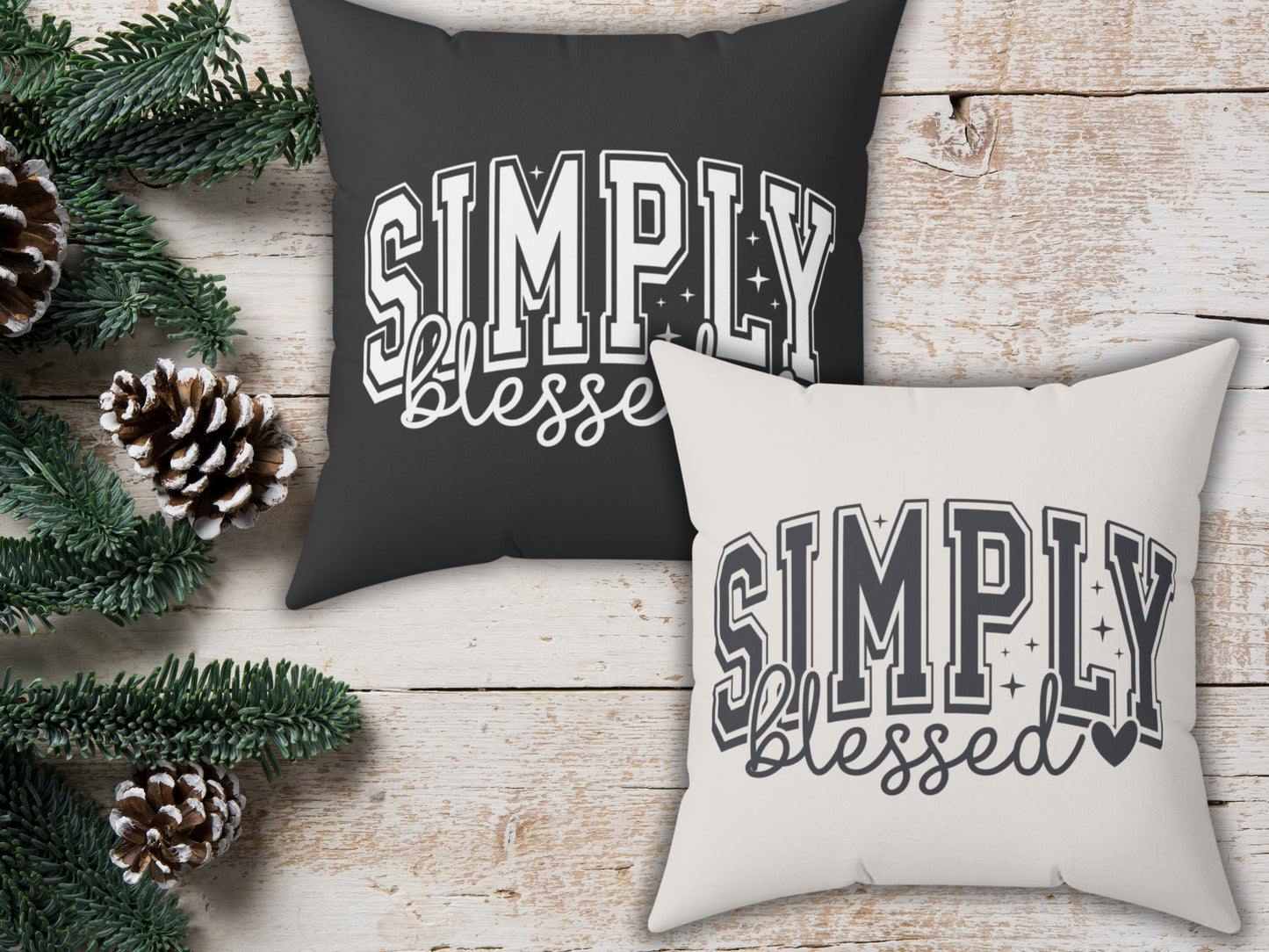 Two pillows with 'Simply Blessed' text on a wooden surface with Christmas decorations.