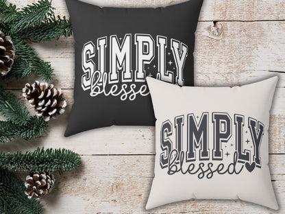 Two pillows with 'Simply Blessed' text on a wooden surface with Christmas decorations.
