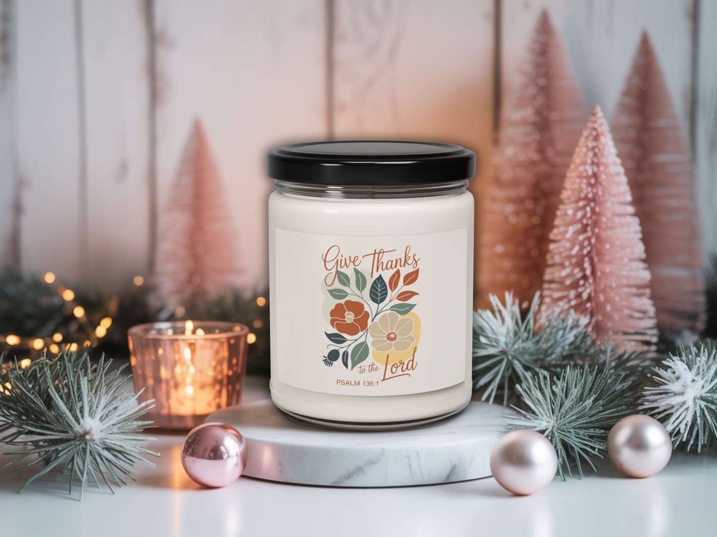 Candle with 'Give Thanks' label in a decorative setting with Christmas trees and lights.