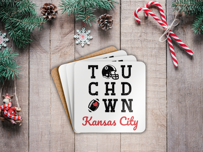Stack of coasters with 'Touchdown Kansas City' text on a wooden surface with Christmas decorations.