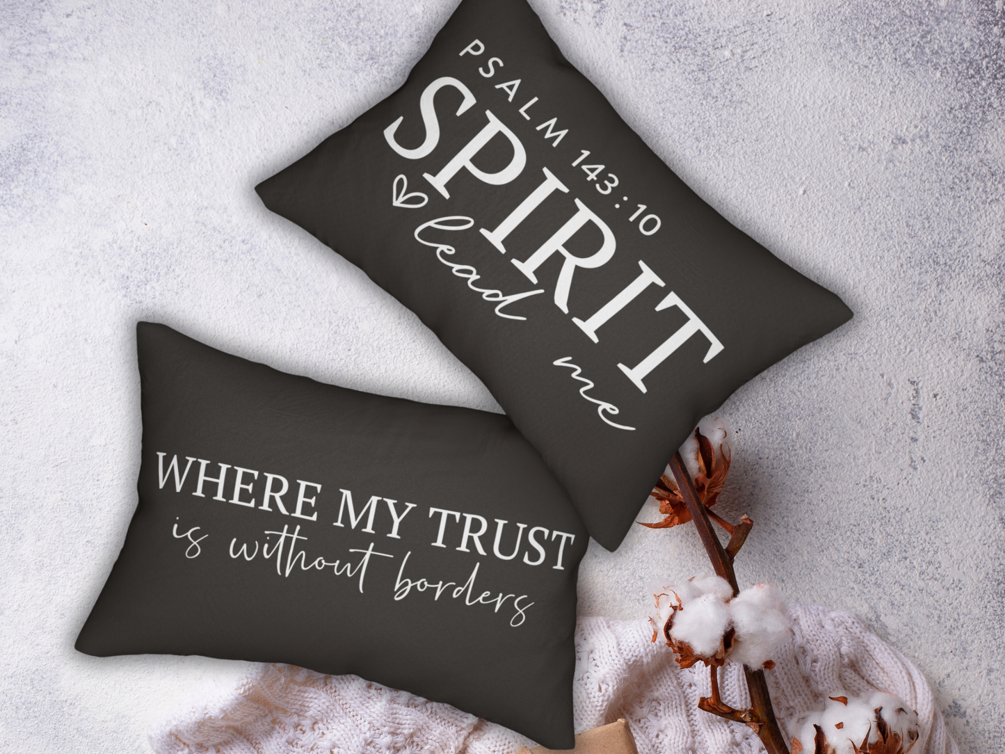 Two black pillows with white text on a textured surface with decorative elements.