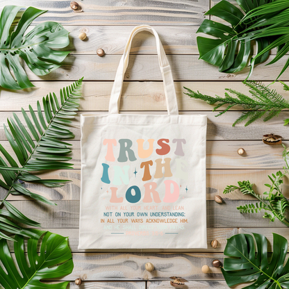 Tote bag with motivational quote surrounded by green leaves on a wooden surface