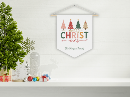 Decorative Christmas banner with colorful trees and 'Merry Christmas' text on a white wall.