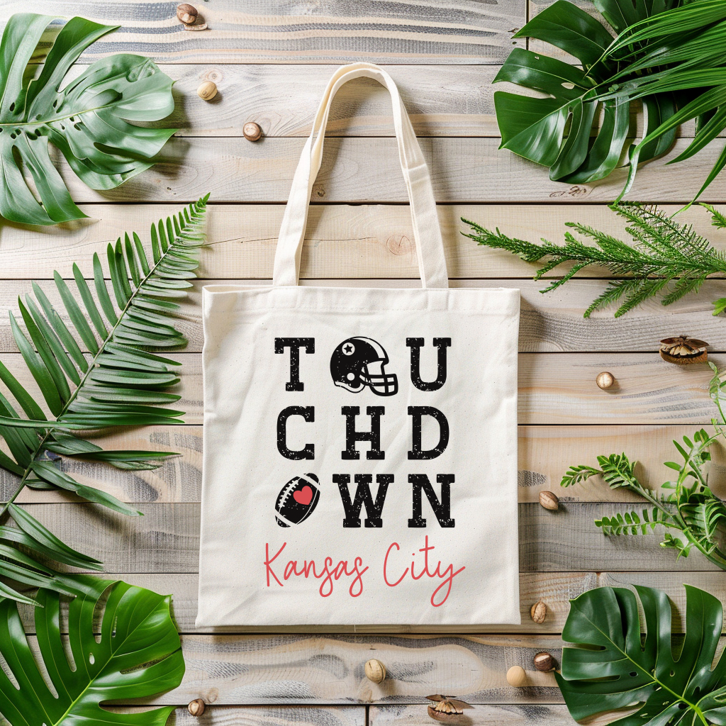 Tote bag with 'Touchdown Kansas City' design on a wooden surface with leaves