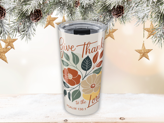 Tumbler with floral design and 'Give Thanks' text, surrounded by Christmas decorations.