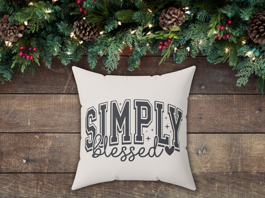 Decorative pillow with 'Simply blessed' text on a wooden surface with Christmas decorations.