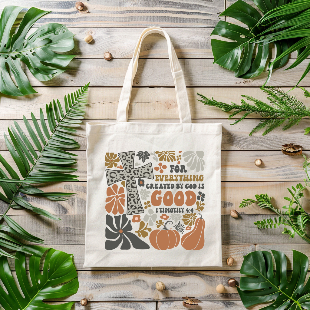 Tote bag with decorative design and text on a wooden surface with leaves
