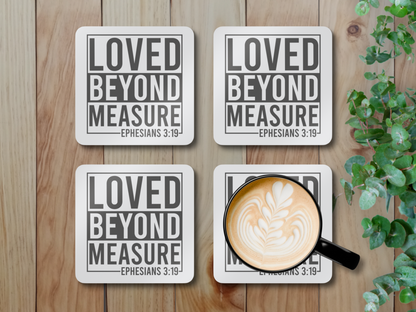 Four coasters on a light wooden surface, one holding a latte in a black cup, styled with greenery.