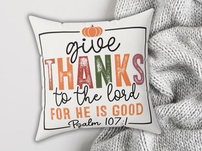 White pillow with Psalm 107:1 design styled with chunky gray knit blanket for a cozy autumn look.