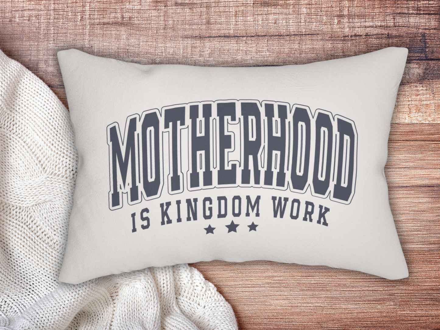 Christian motherhood pillow styled on a wooden surface with a cozy white knit blanket.
