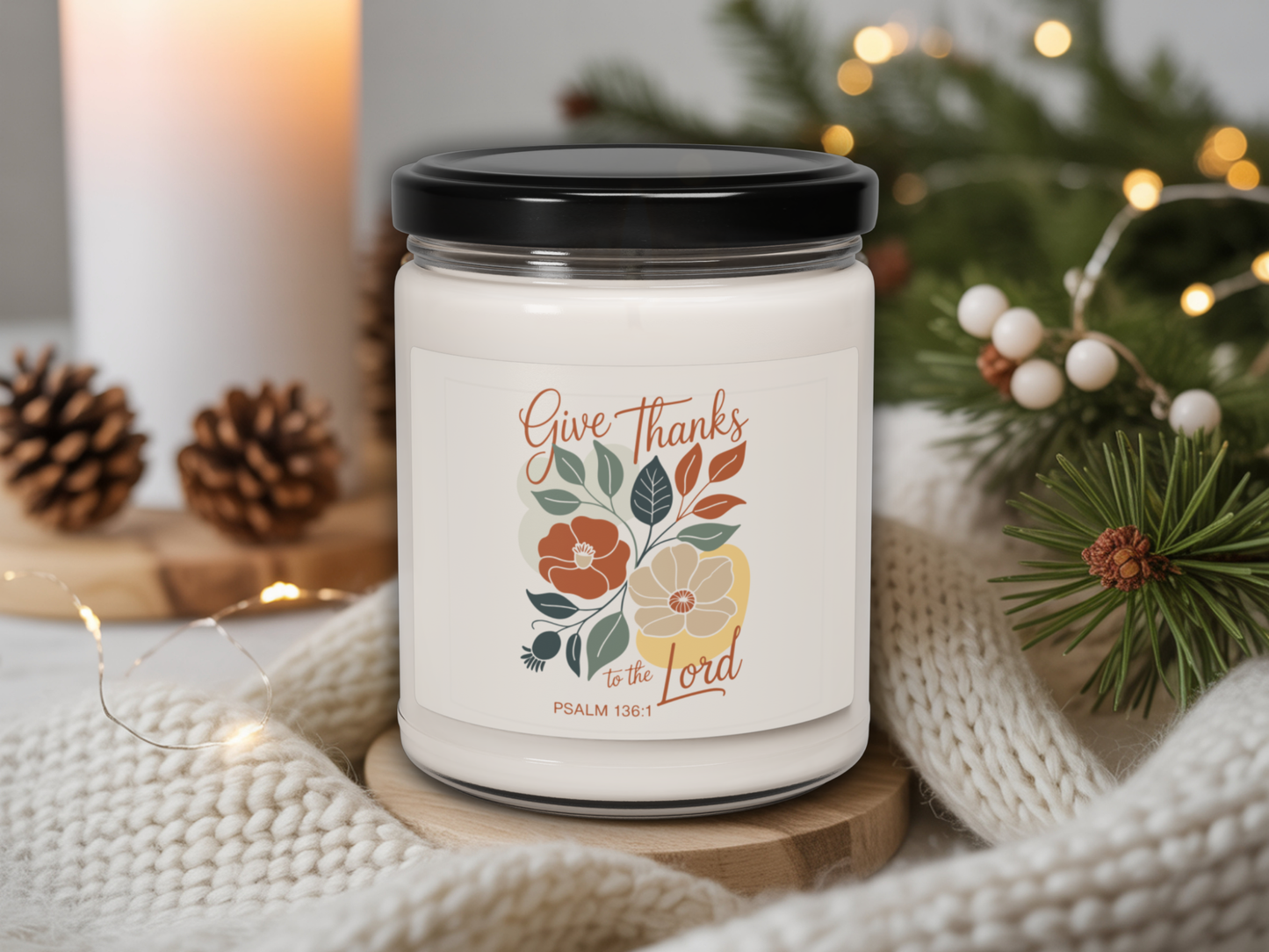 Candle jar with 'Give Thanks to the Lord' text and floral design, surrounded by Christmas decor.