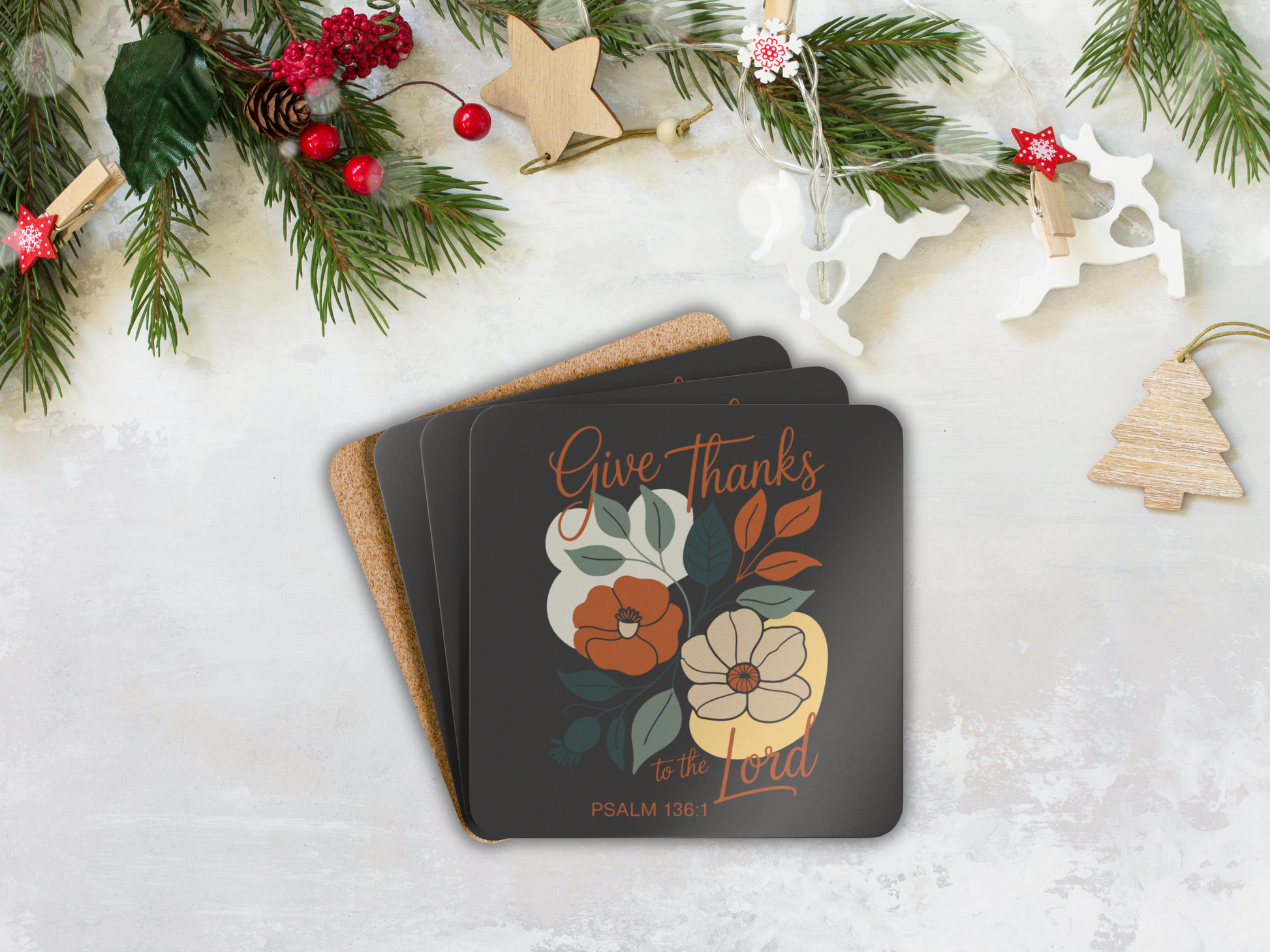 Stack of coasters with floral design and 'Give Thanks' text on a snowy background with Christmas decorations.