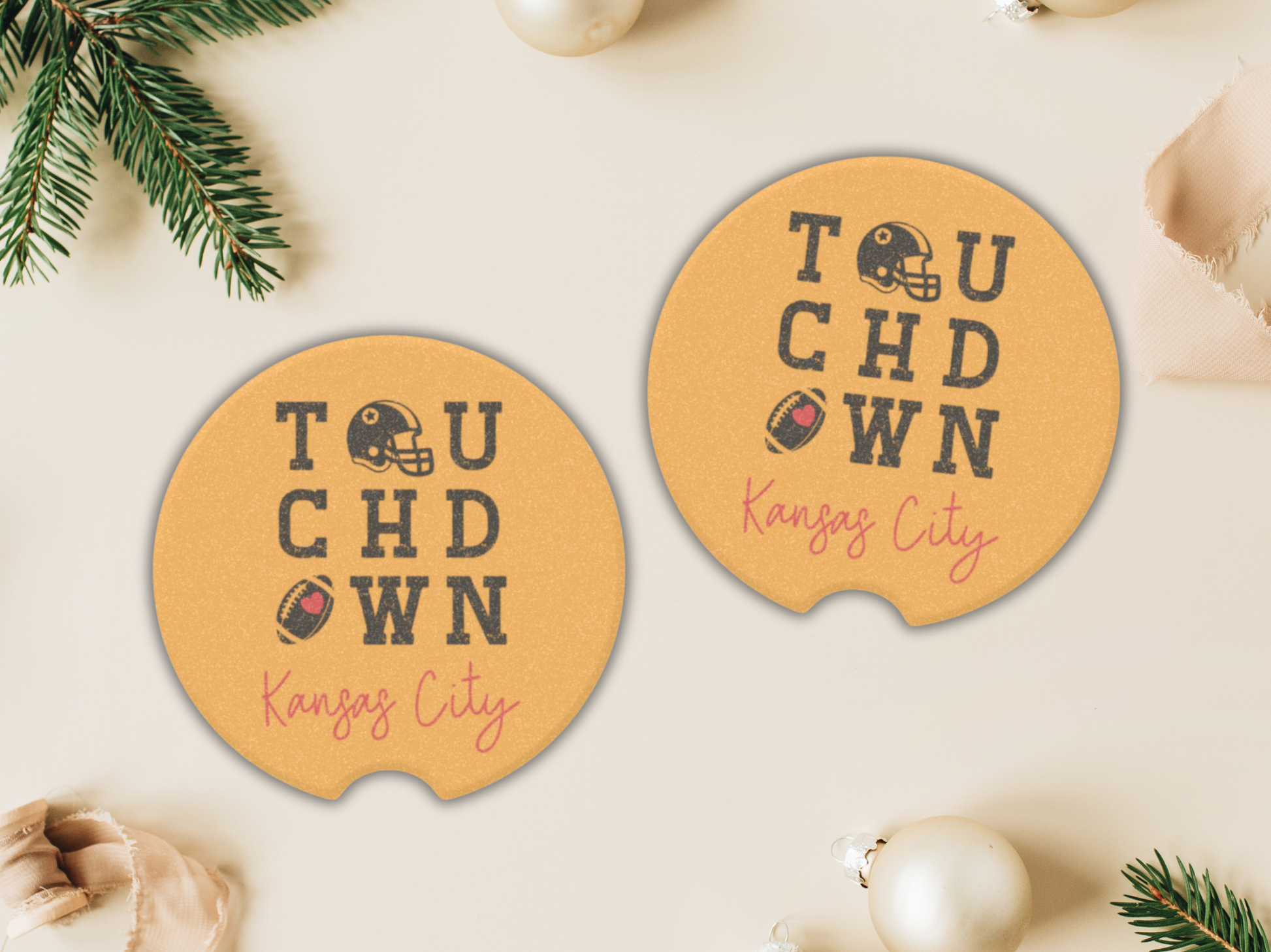 Two round coasters with 'Touchdown Kansas City' text on a beige surface with Christmas decorations.
