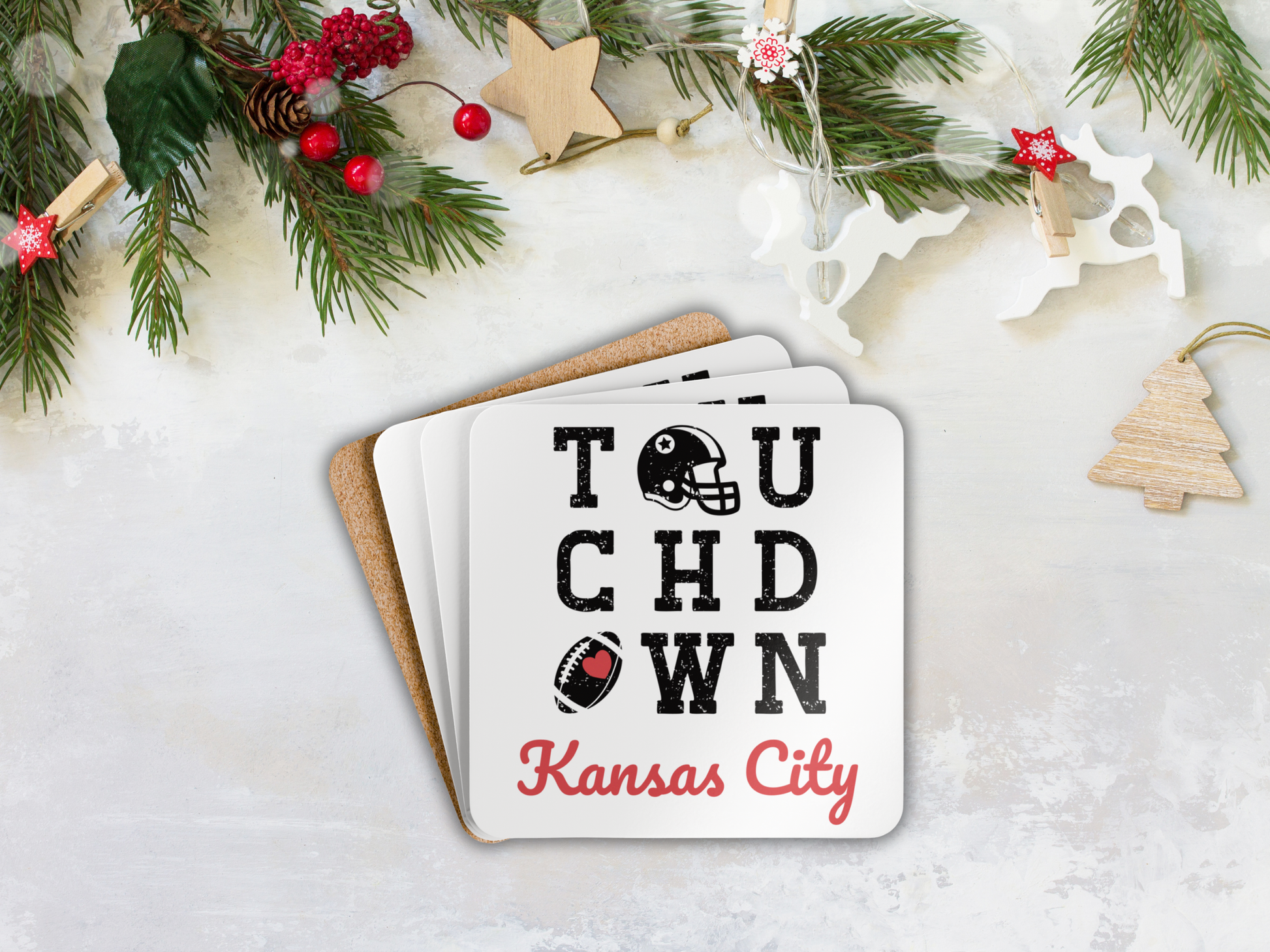 Stack of coasters with 'Touchdown Kansas City' text on a snowy background with Christmas decorations.