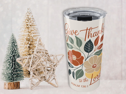 Tumbler with 'Give Thanks to the Lord' text and floral design, surrounded by decorative trees on a light background
