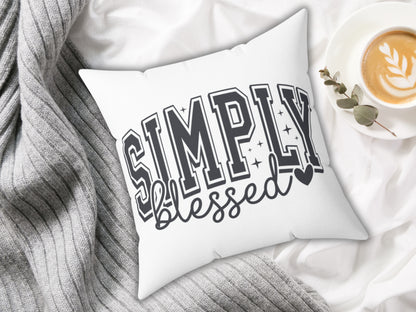 White pillow with 'Simply Blessed' text on a soft fabric background with a cup of coffee.