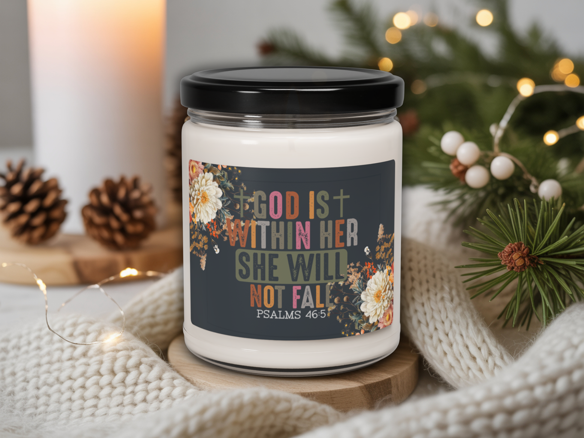 Candle jar with motivational quote on a decorative setting with lights and pine cones.