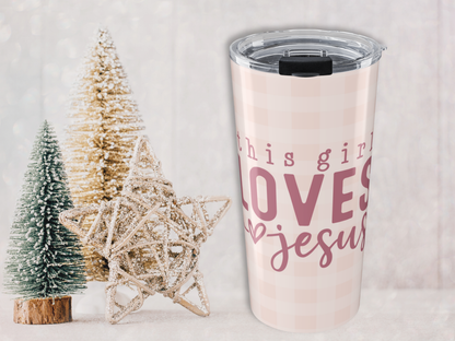 Tumbler with 'this girl loves Jesus' text next to Christmas trees on a light background