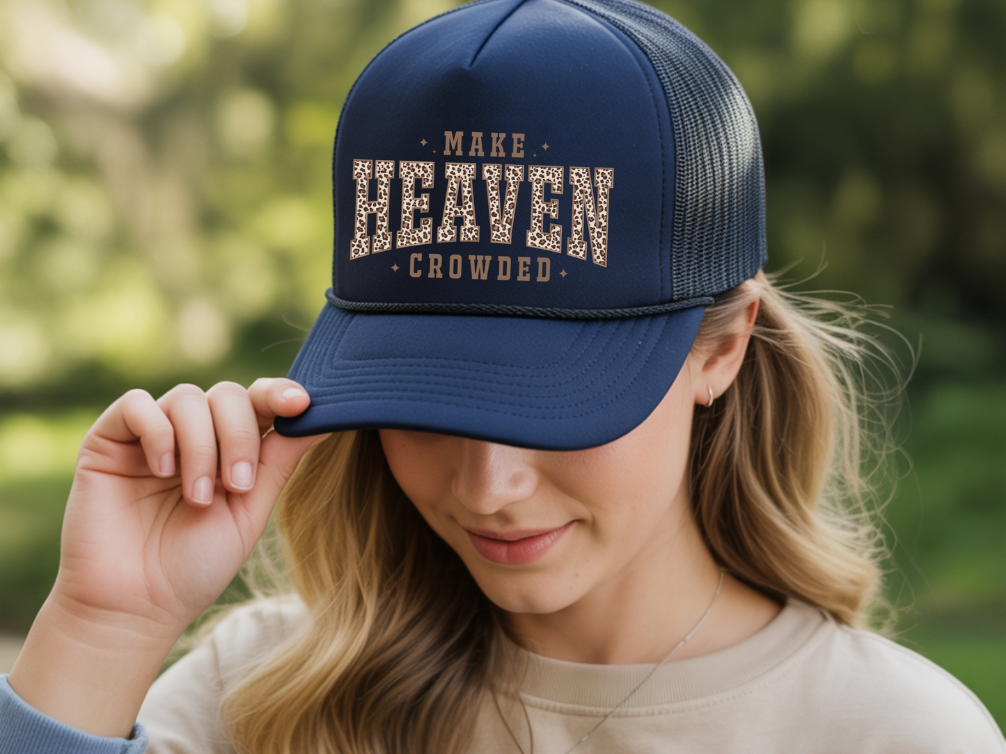 Person wearing a navy blue cap with 'Make Heaven Crowded' text, outdoors.