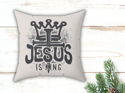 Pillow with 'Jesus is King' text on a wooden surface with Christmas decorations.