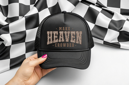 Black cap with text held by a hand against a checkered background