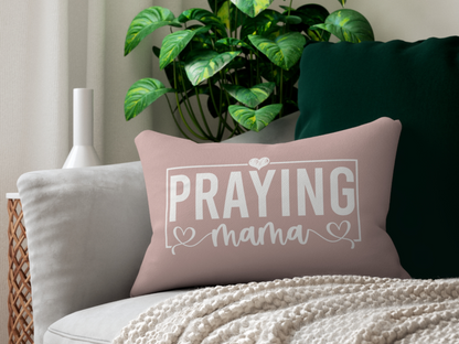 Decorative blush pink pillow with “Praying Mama” lettering placed on a modern gray couch with green accent pillow, knit throw, and houseplants.