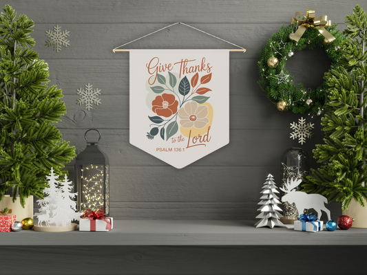 Decorative wall banner with 'Give Thanks to the Lord' text, surrounded by Christmas decorations on a gray wall.