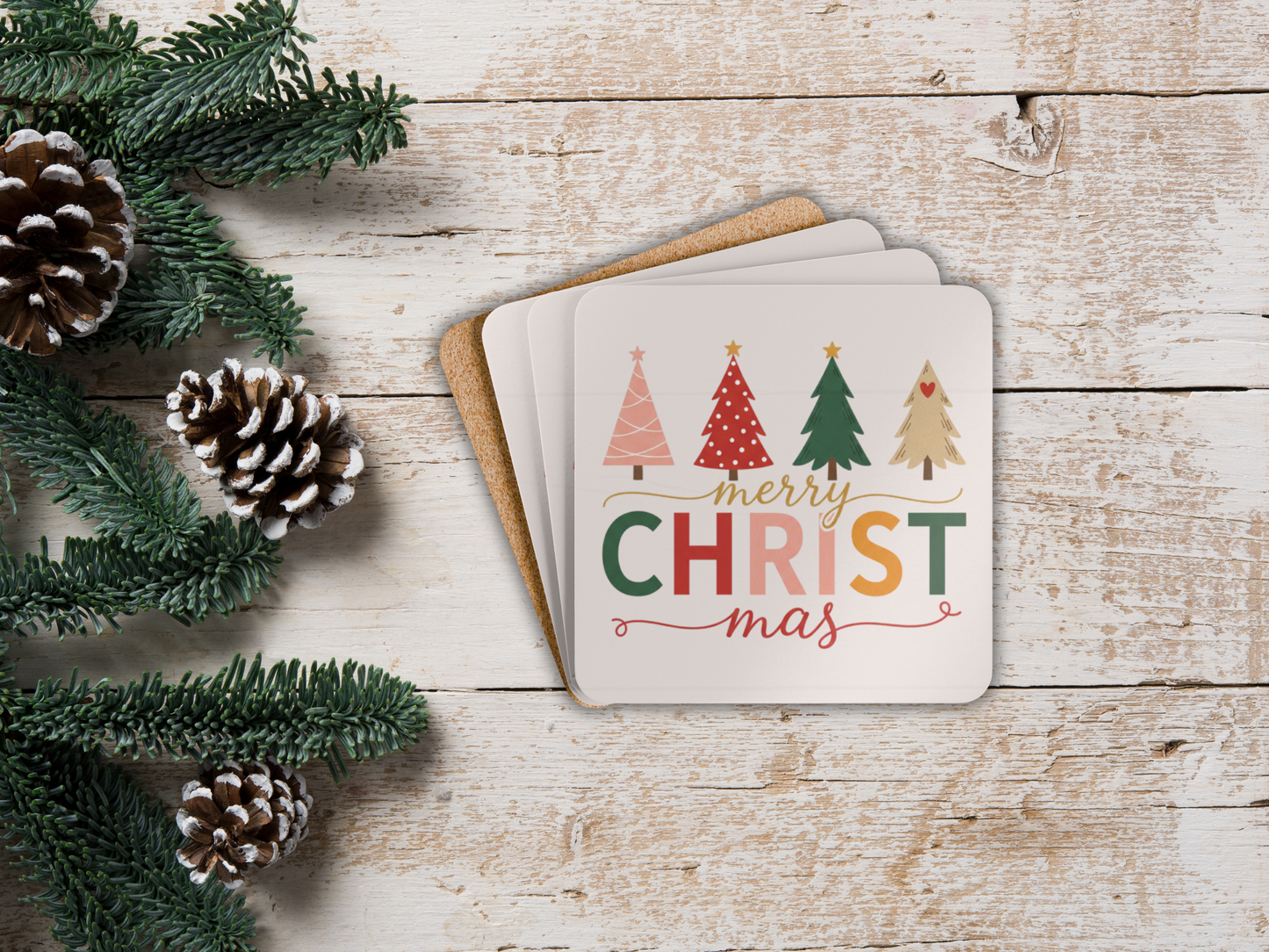 Coasters with Christmas design on a wooden surface with pine cones and greenery.