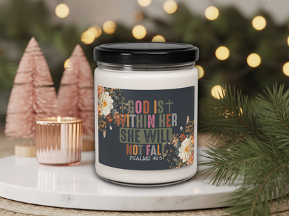Candle jar with motivational quote label on a decorative surface with Christmas trees and lights.