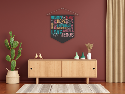 Decorative wall hanging with text above a wooden cabinet in a room with a plant and curtains.