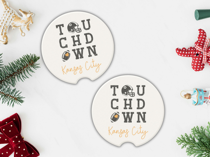 Two 'Touchdown Kansas City' coasters on a white surface with Christmas decorations.