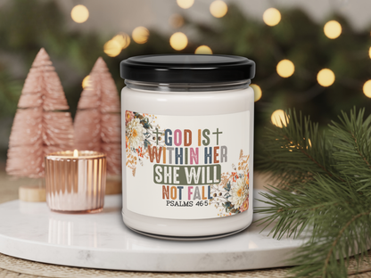 Candle jar with motivational quote on a decorative surface with Christmas trees and lights.