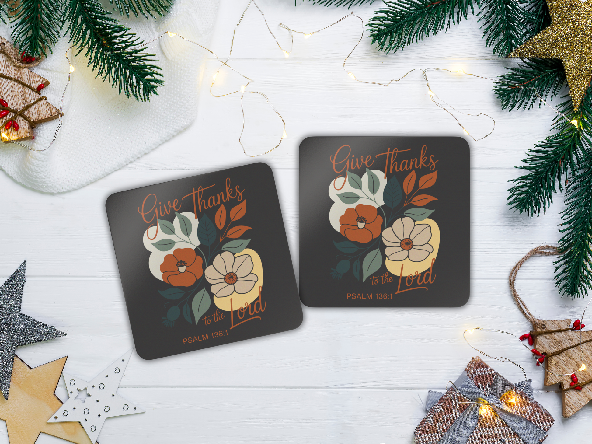 Two coasters with floral design and text on a white surface with Christmas decorations.
