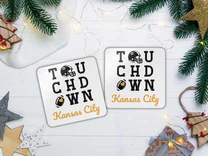 Two 'Touchdown Kansas City' coasters on a festive background with Christmas decorations.
