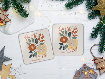 Two coasters with floral designs and text on a white surface with Christmas decorations.