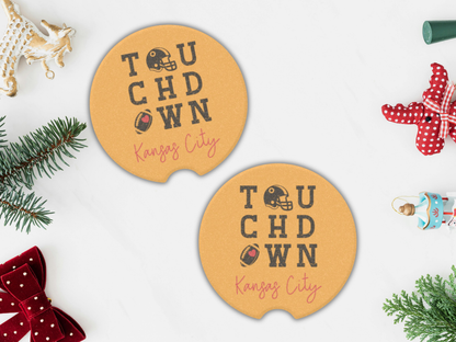 Two round yellow coasters with 'Touchdown Kansas City' text on a white background with Christmas decorations.