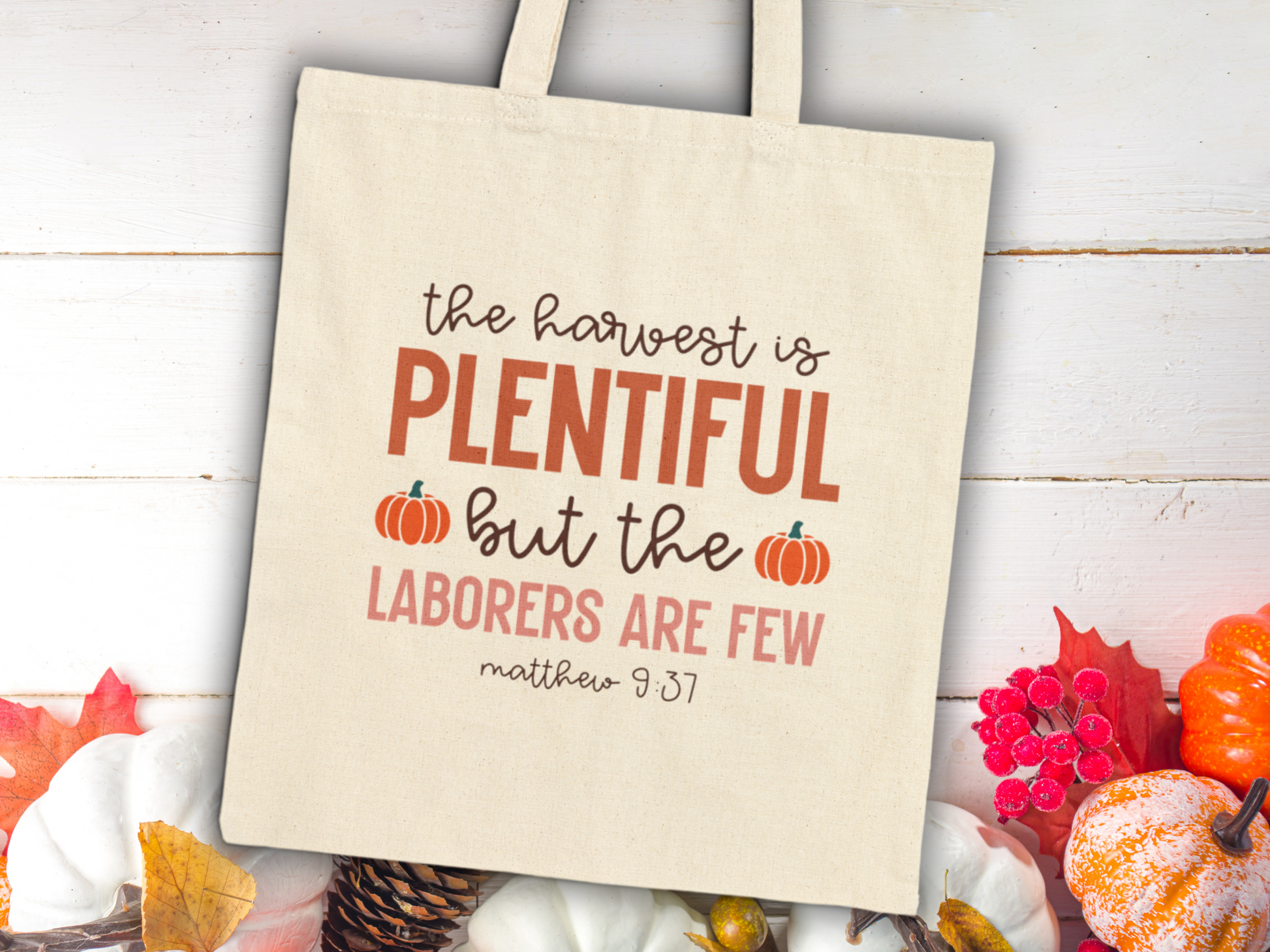 Tote bag with "The harvest is plentiful but the laborers are few, Matthew 9:37" printed. Autumn elements like pumpkins and leaves surround it.