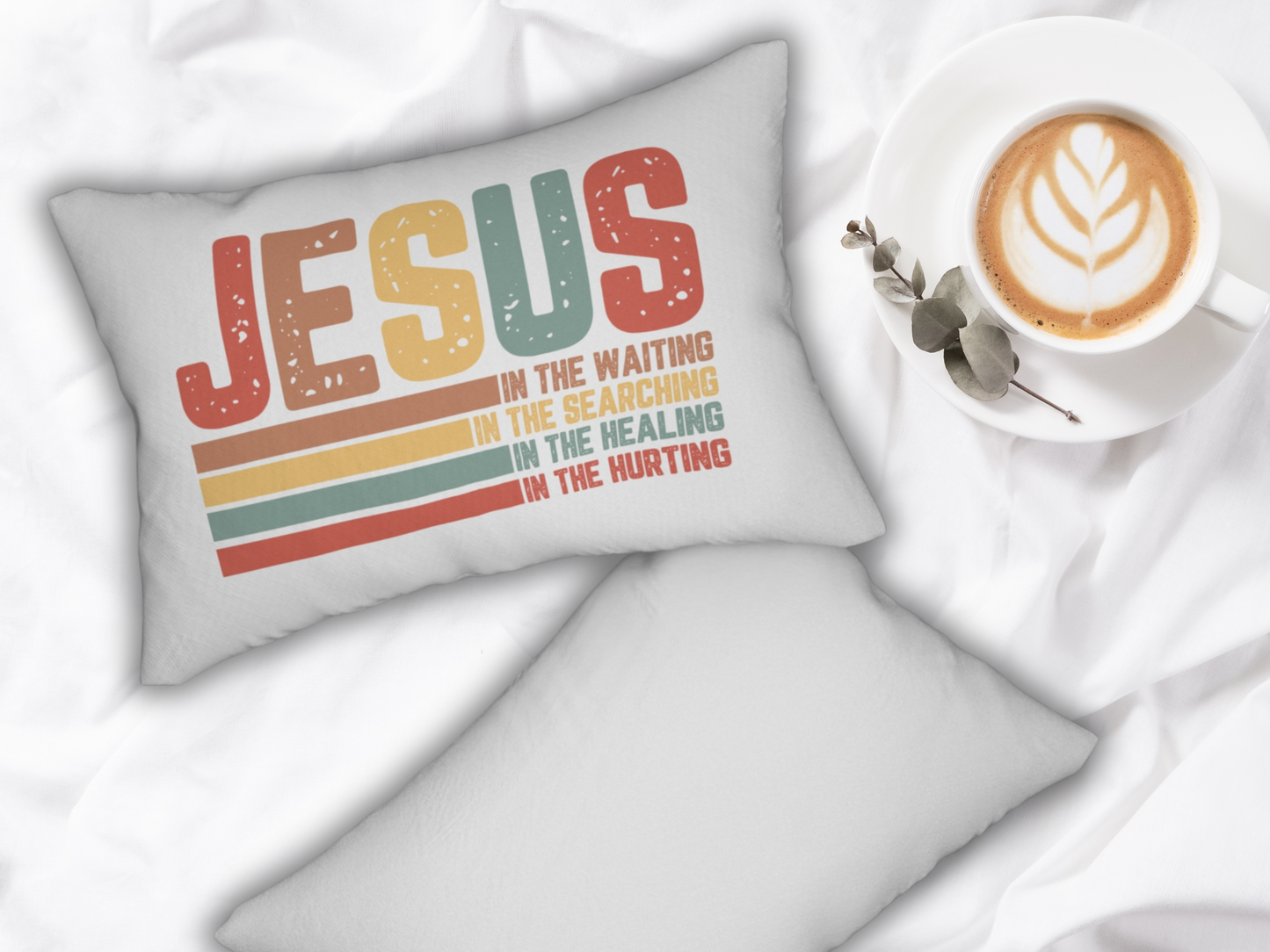 Pillow on a white bed with coffee, saucer, and eucalyptus branch for a cozy morning look.