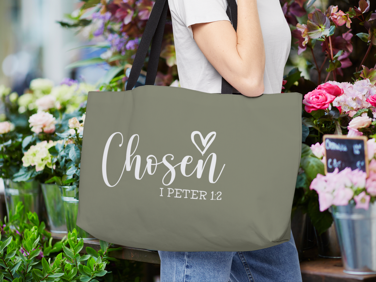“Chosen” weekender tote carried over the shoulder in a flower shop surrounded by colorful blooms.