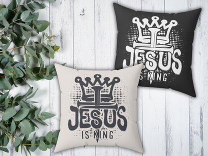 Two pillows with 'Jesus is King' design on a wooden surface with greenery.