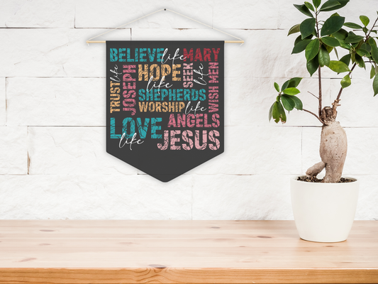 Decorative wall hanging with religious text on a wooden surface with a plant in the background.