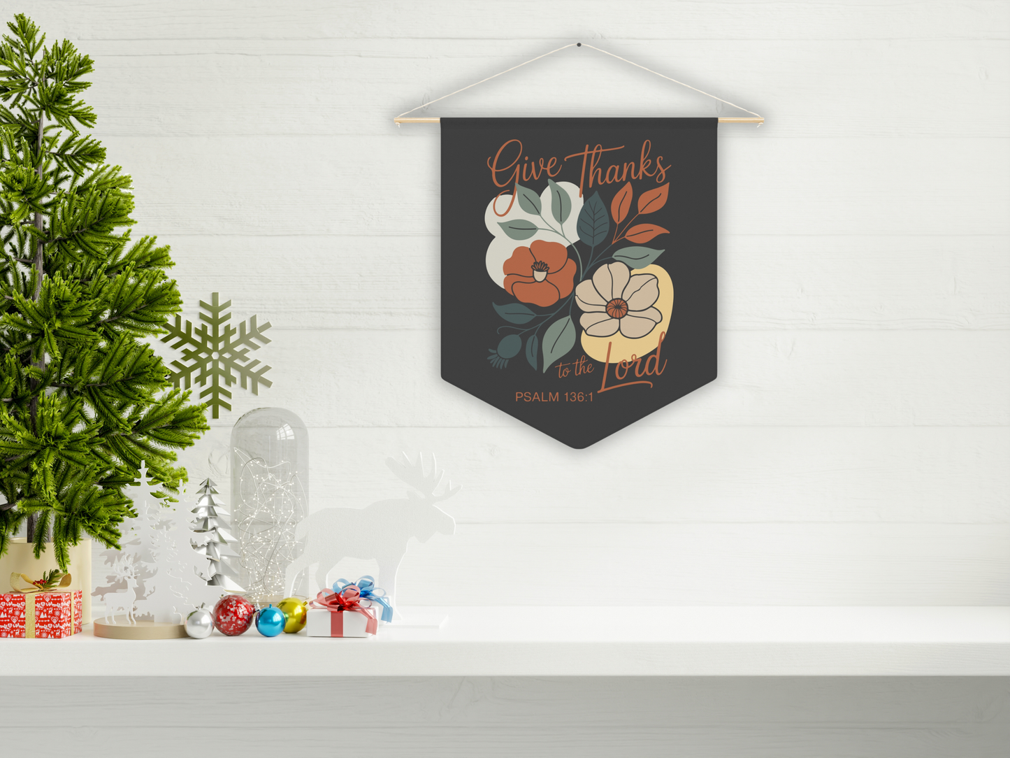 Decorative wall hanging with floral design and text on a white shelf with Christmas decorations.