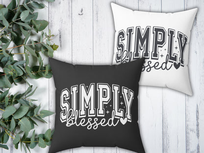 Two pillows with 'Simply Blessed' text on a wooden surface with greenery.