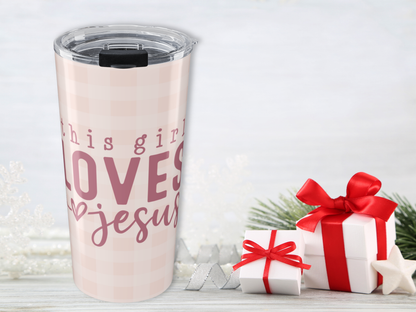 Tumbler with 'This girl loves Jesus' text next to gift boxes on a light background