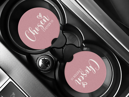 Car drink holder with pink 'Chosen' coasters inside a car.